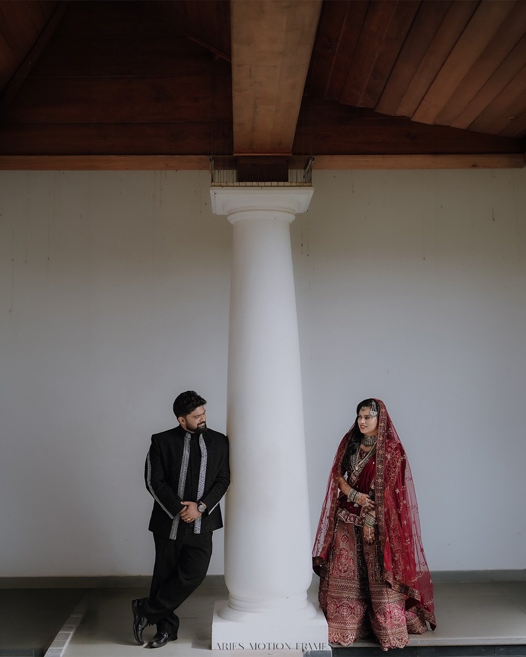 Newlyweds exchanging a smile beside a white column